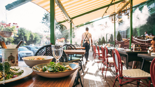 Outdoors summer terrace cafe with served table and waiter