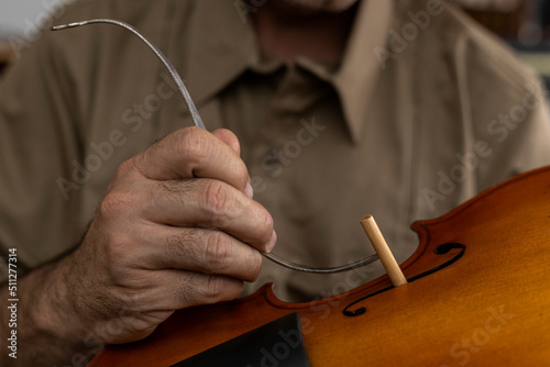 Latin American luthier placing a sound post between the top and the bottom of the violin. Stringed instruments concept
