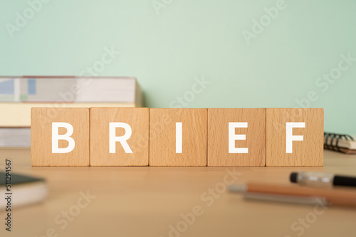 要約・簡潔のイメージ｜「BRIEF」と書かれたブロックが置かれたデスク