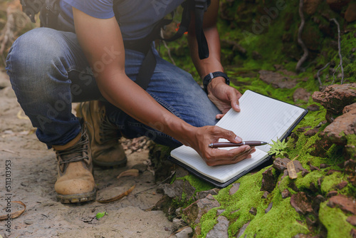 Crop image of Biologist or botanist recording information about small tropical plants in forest. The concept of hiking to study and research botanical gardens by searching for information.