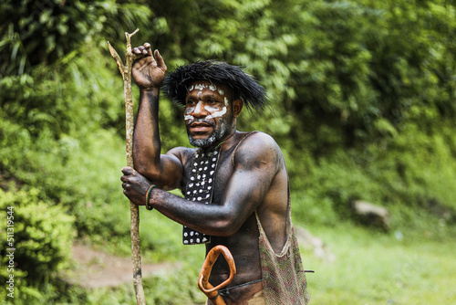 Portrait of Dani Tribe man wearing koteka, traditional clothes of Papua. Dani tribe men ready to hunt animal prey in the jungle. 