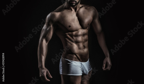 Sexy male model with bare nude torso. Sexy young handsome naked man on dark background. Seductive gay.
