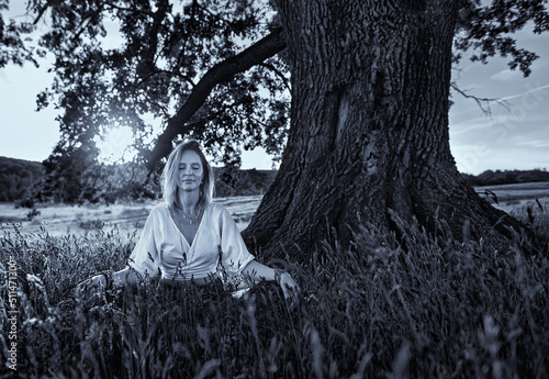Young woman doing yoga meditation under a tree