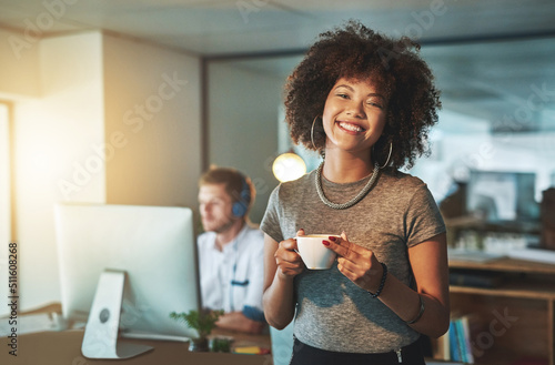 Day shifts are for sissies. Portrait of a young designer working late with her colleague blurred in the background.