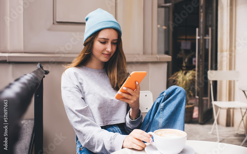 Young millennial female using social network application on mobile phone for communication. Caucasian hipster girl holding smartphone in silicone case. Teenager browsing online with internet data