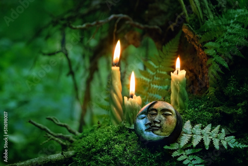 candles and symbolic moon amulet on dark forest background. pagan Wiccan, Slavic traditions for Litha. Witchcraft, esoteric spiritual ritual, magic practice. Mysticism, divination, modern occultism