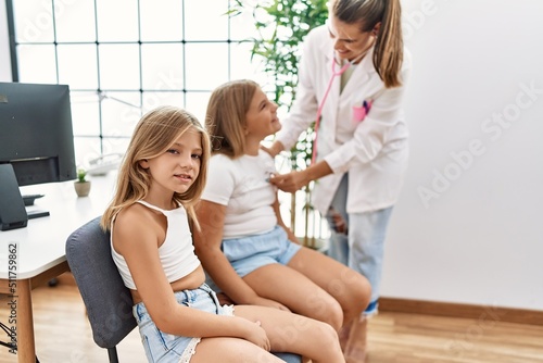 Mother and daughters doctor and patient auscultating heart having medical session at clinic