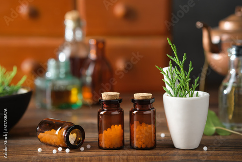 Bottles of homeopathic granules, cabinet with homeopathic remedies and tincture bottles on background. Homeopathy medicine concept.