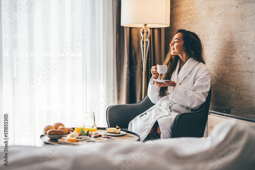 Woman eating breakfast in the hotel room. Room service breakfast in hotel room.