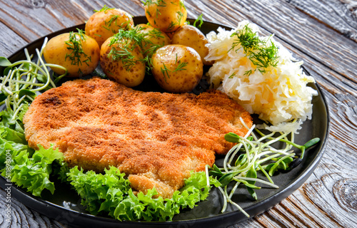 Pork cutlet coated with breadcrumbs with potatoes and cabbage