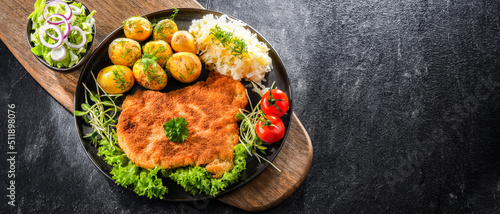 Pork cutlet coated with breadcrumbs with potatoes and cabbage