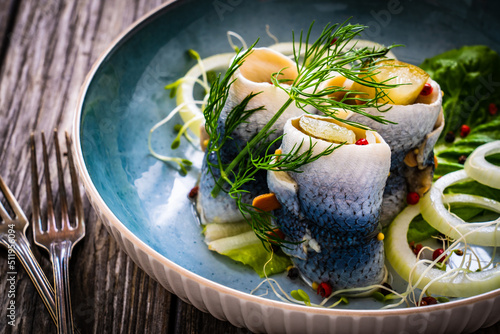 Marinated herring fillets with pickled cucumber, dill and onion on wooden table 