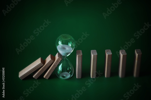 domino effect concept with wooden tiles blocked by hourglass with background