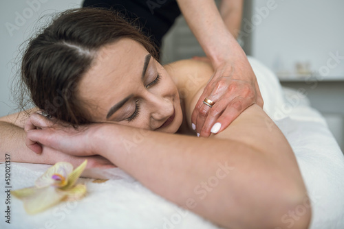 close up of female masseur doing curative healing massage on female client shoulder and back in spa