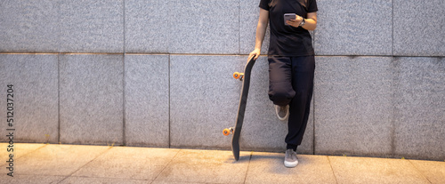 One skateboarder use mobile phone on city