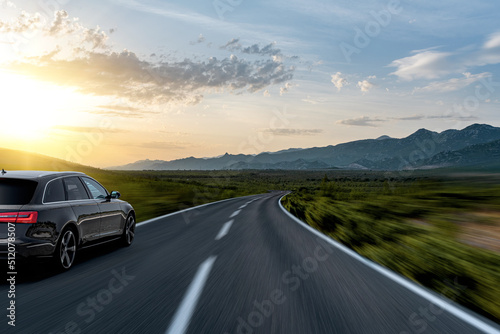 Black car on a scenic road. Car on the road surrounded by a magnificent natural landscape.