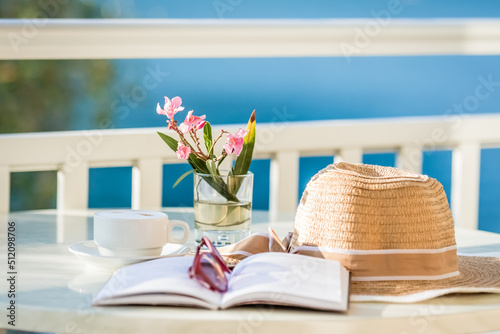 Kapelusz słoneczny oraz książka leży na stoliku na balkonie w pokoju hotelowym z balkonem