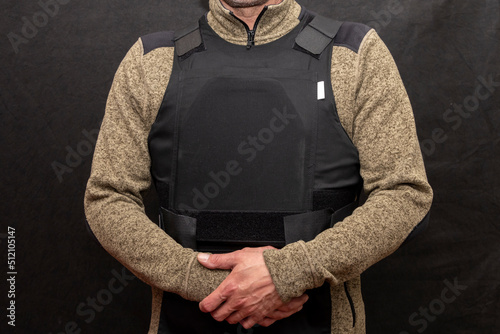 A muscular military man in a bulletproof vest on a black background.