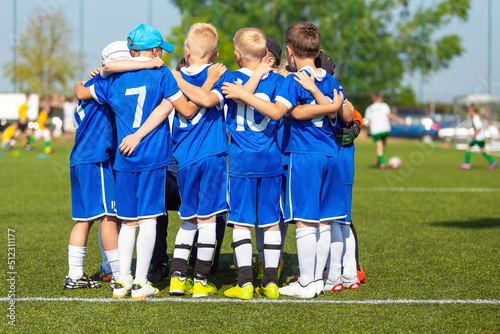 Sporty players huddling in a circle on the field. Motivated youth soccer team cheering on court. Team captain talking to a group of soccer friends. Happy football team in blue soccer uniforms