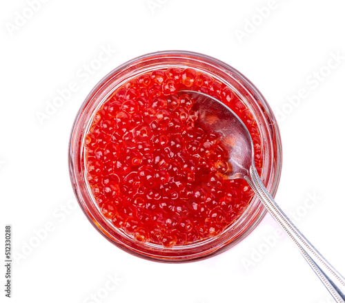 Glass jar with red caviar and metal spoon isolated on white background.