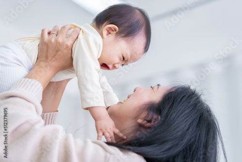 baby girl with asian mom smiling baby happily playing together in bed in the bedroom at home