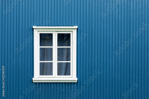 Window on a blue painted wall, colorful house, architecture detail in Reykjavik, Iceland