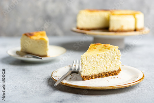 Cottage cheese casserole on shortbread on a white ceramic plate on a concrete light gray background. Portioned sliced cheesecake pie.