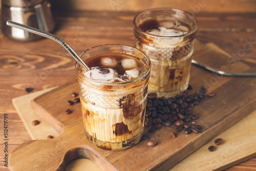 Glasses of cold brew coffee with milk and straw on wooden board