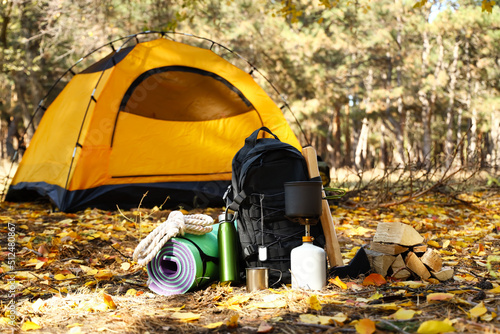 Tourist's survival kit and camping tent in autumn forest