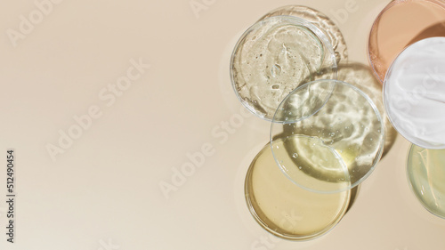 Various cosmetic products in Petri dishes on beige background view from above. Copy space