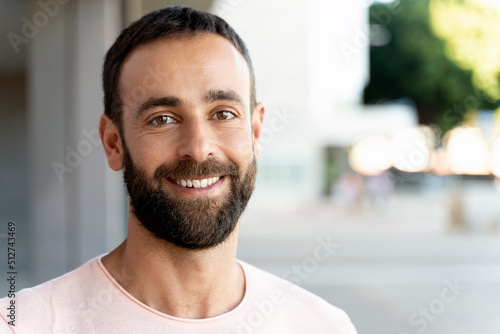 Portrait of smiling handsome man looking at camera on the street, copy space. Happy confident client after beard cut in barbershop 