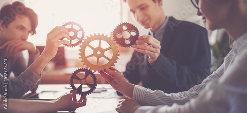 Group of people working in the office while putting together cogwheels.