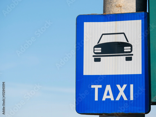 Blue taxi sign station against blue sky.