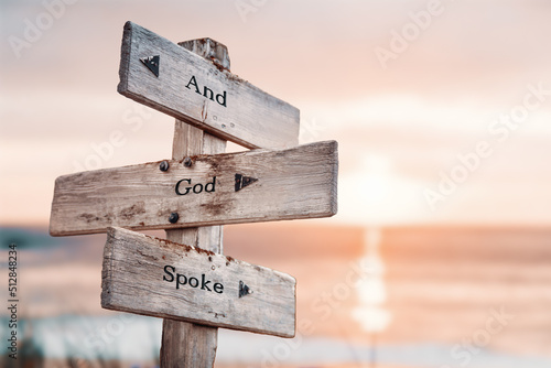 and god spoke text quote on wooden crossroad signpost outdoors on beach with pink pastel sunset colors. Romantic theme.
