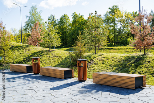 Beautiful landscape design of the city park, a pleasant place for walks and recreation of citizens, wooden benches for sitting, a sidewalk in the park.