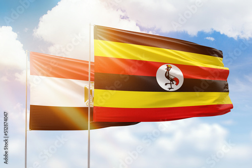Sunny blue sky and flags of uganda and egypt