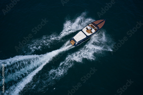 Luxurious wooden boat fast movement on dark water..Classic Italian wooden boat fast moving aerial view. Top view of a wooden powerful motor boat.