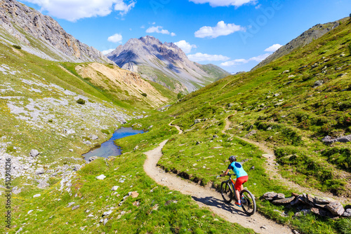 Woman tourist cycling on mtb bike in beautiful Alpisella valley on sunny summer day, Alps Mountains, Italy