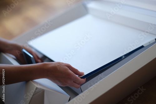 Tbilisi, Georgia - May 25, 2022: Woman removes white protective film from New iMac monitor