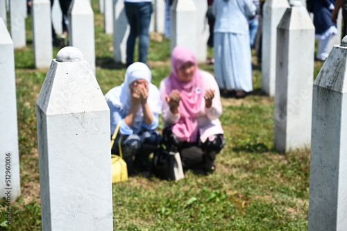 Gravestones in Srebrenica Genocide Memorial in Potocari. Cemetery for the victims of the 1995 genocide in Bosnia and Herzegovina. Women cry near gravestone.
