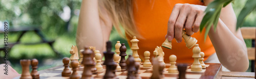 Cropped view of woman playing blurred chess in park, banner.