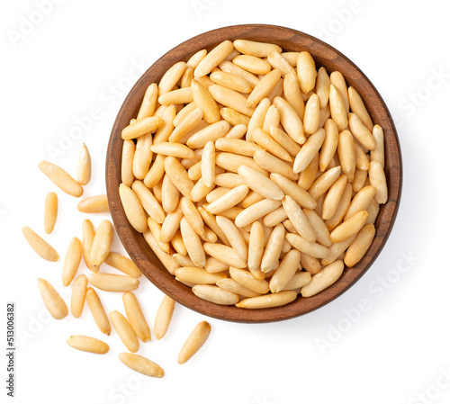 Roasted pine nuts in the wooden bowl, isolated on white background, top view.