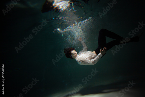 Sink. A young man is going to the bottom. A guy in a white shirt and trousers falls under the water, calmness and acceptance of fate