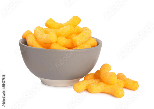 Many tasty cheesy corn puffs in bowl isolated on white