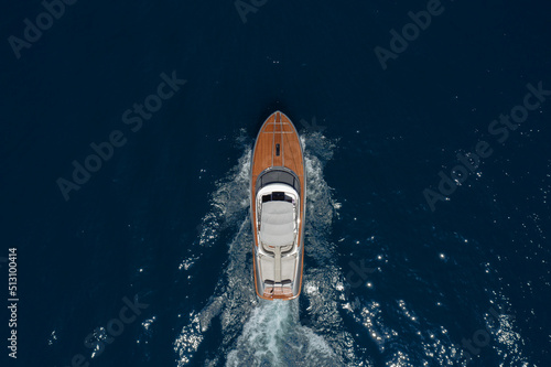 Luxurious wooden boat fast movement on dark water..Classic Italian wooden boat fast moving aerial view. Top view of a wooden powerful motor boat with an awning.