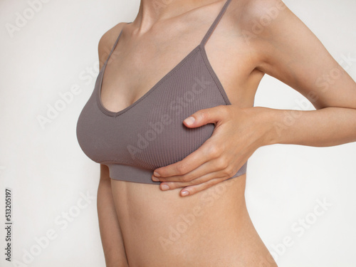 Closeup cropped portrait young woman with breast pain touching chest woman examining breast mastopathy or cancer plastic surgery White background Healthcare concept. women Health. White background
