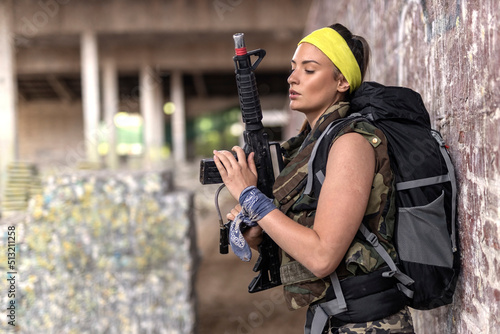 Beautiful woman in paintball club with gun looking all arround