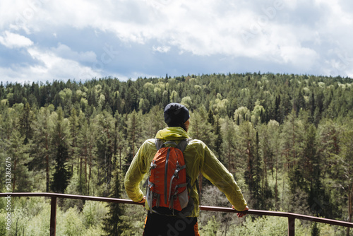 Observation deck on the mountain, a person admires the landscape from a height, the view of a man with a backpack on a hike, tregging in the mountains, taiga in Russia, summer vacation