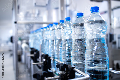 Plastic bottles on conveyor belt being filled with drinking water.