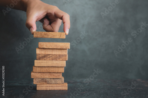 Hand place wooden block stacked concept of prevent collapse or crash of financial business and risk management or strategic planning and insurance.